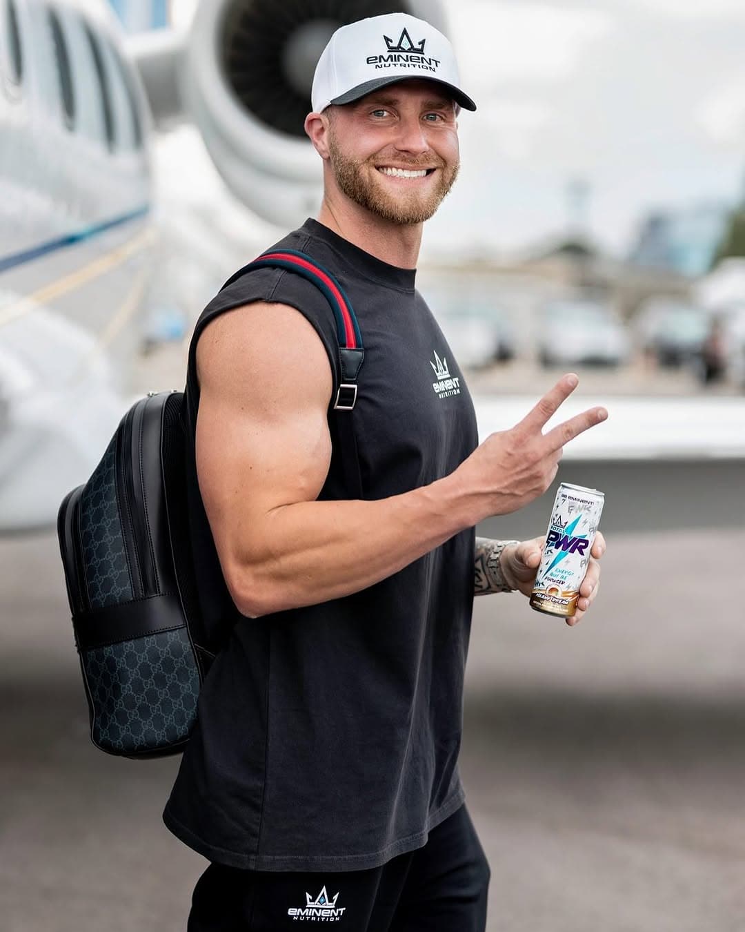 Casey Barnette on the tarmac in an Eminent hat, holding a Royal PWR can